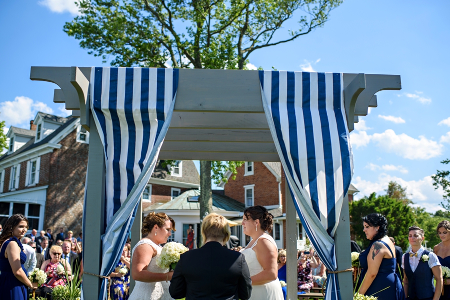 Two brides exchanging vows in front of friends and family.